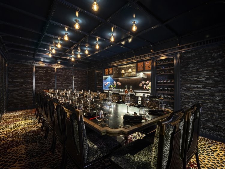 Luxurious dining room with a long table, elegant chairs, dim lighting, and decorative shelves, reminiscent of Tattu Restaurant in Leeds for private dining